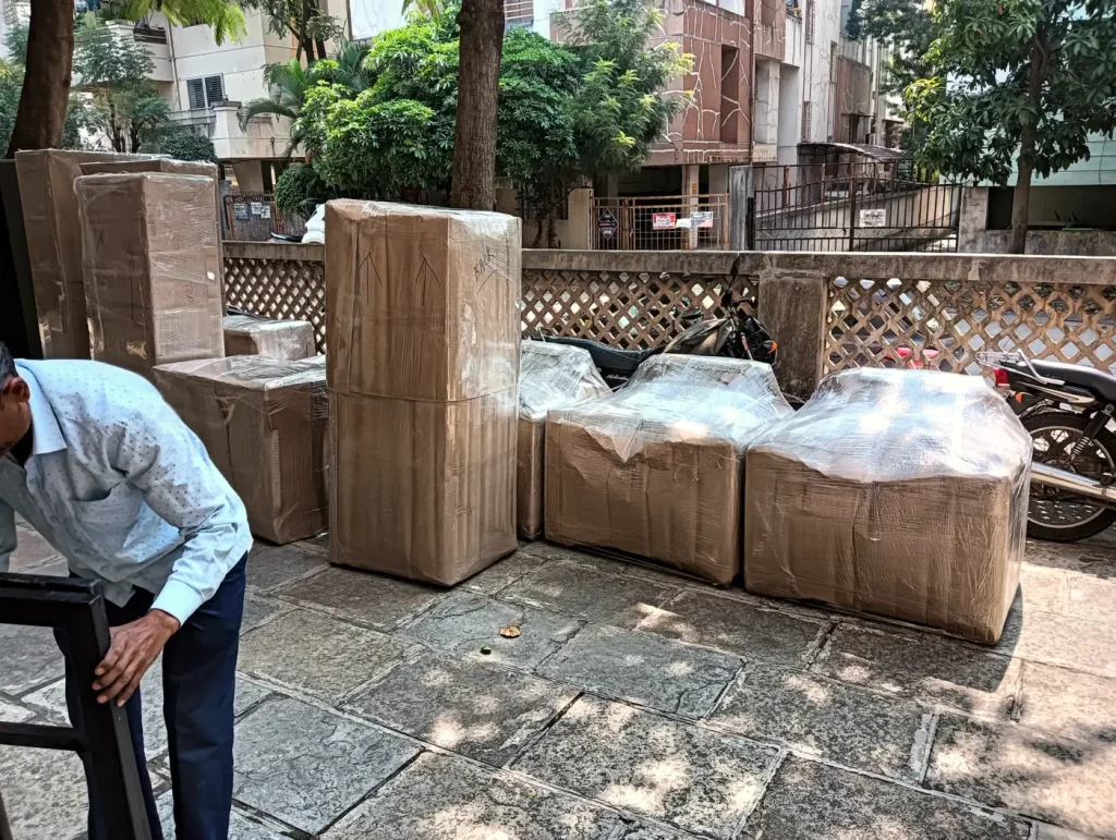 Wrapped furniture lined up outdoors with a packer at work