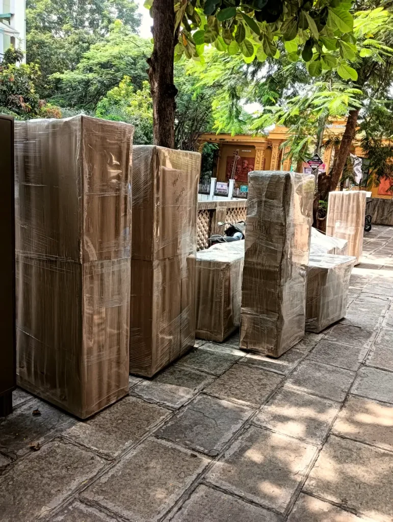 Wrapped wardrobes and furniture under trees, ready to load