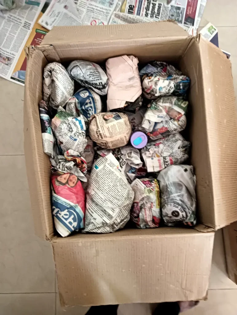 Kitchen items wrapped in paper inside a carton